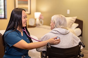 A nurse checking the heartbeat of an elderly woman