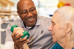 A physical therapist helping a woman lift weights at Skye Canyon